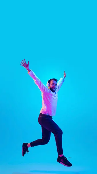 Caucasian mans portrait isolated on blue studio background in neon light. Concept of human emotions, facial expression, sales, ad.