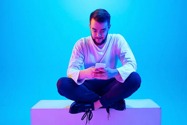 Caucasian mans portrait isolated on blue studio background in neon light. Concept of human emotions, facial expression, sales, ad.