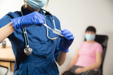 Hastanede enjekte edilen şırıngayı kullanarak hastaya aşı yapan doktor ya da hemşire.