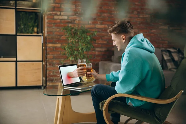 年轻人在虚拟视频通话中与朋友见面时喝啤酒。远程在线会议，在家里用笔记本电脑聊天. — 图库照片