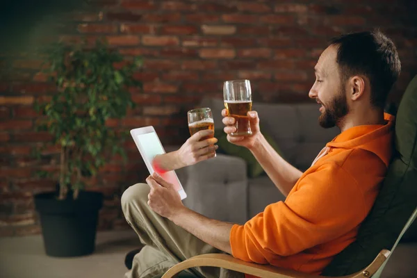 年轻人在虚拟视频通话中与朋友见面时喝啤酒。远程在线会议，在家用平板电脑聊天. — 图库照片
