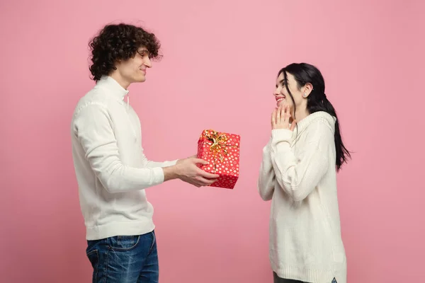 Junges, schönes verliebtes Paar auf rosa Studiohintergrund. Valentinstag, Liebe und Emotionen — Stockfoto