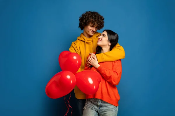 Hermosa pareja enamorada en el fondo del estudio azul. Día de San Valentín, concepto de amor y emociones —  Fotos de Stock