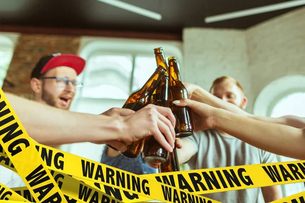Cierra las manos tintineando botellas de cerveza en el bar con cintas limitadoras Lockdown, Coronavirus, Cuarentena, Advertencia - cerrando bares y clubes nocturnos durante la pandemia — Foto de Stock
