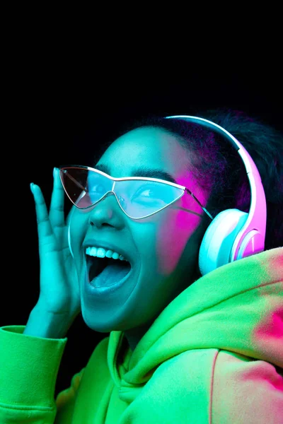 Ritratto di donna afro-americana isolato su sfondo scuro da studio in luce neon multicolore — Foto Stock