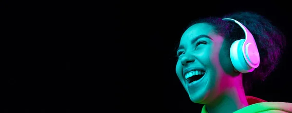 Africano-americano mulheres retrato isolado no escuro estúdio fundo em multicolorido néon luz — Fotografia de Stock