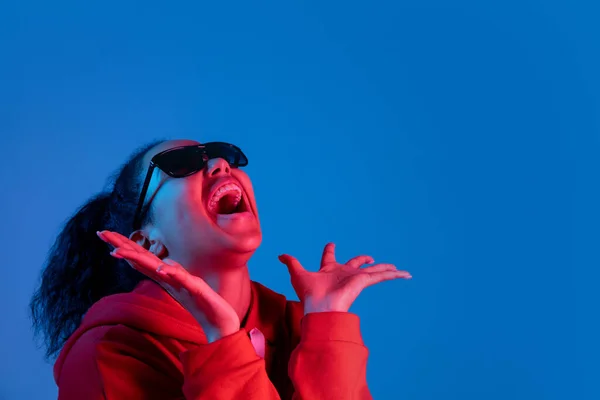 Retrato de mujeres afroamericanas aislado en fondo de estudio azul en luz de neón multicolor —  Fotos de Stock