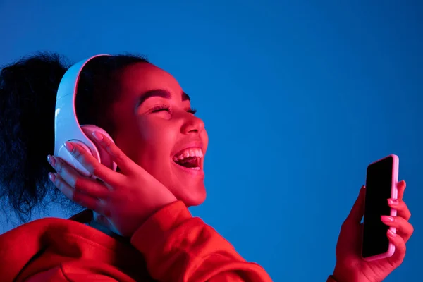 Africano-americano mulheres retrato isolado no fundo estúdio azul em luz de néon multicolorido — Fotografia de Stock