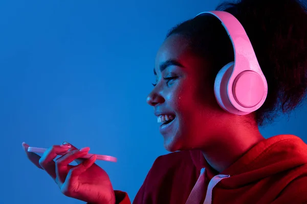 Africano-americano mulheres retrato isolado no fundo estúdio azul em luz de néon multicolorido — Fotografia de Stock