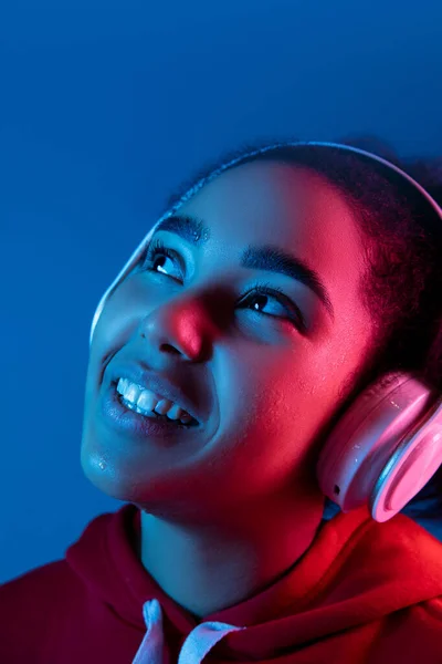 Afroamerykanki portret odizolowany na niebieskim tle studio w kolorowe neonowe światło — Zdjęcie stockowe