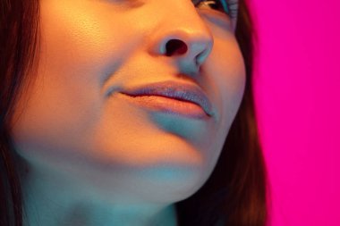 Kafkas güzel kadın portresi pembe stüdyo arka planında çok renkli neon ışıklarla izole edilmiş.