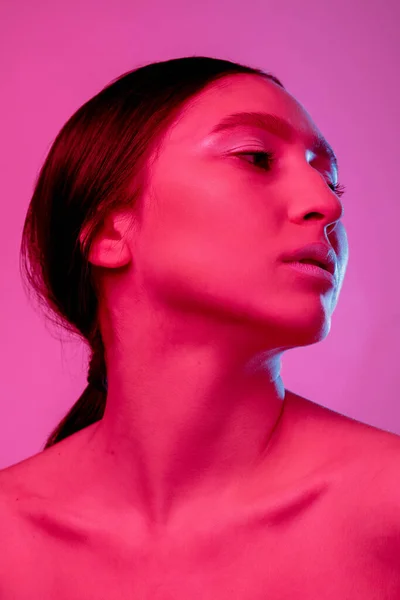Krásná východní žena portrét izolované na růžové pozadí studia v neonovém světle, monochromatický — Stock fotografie