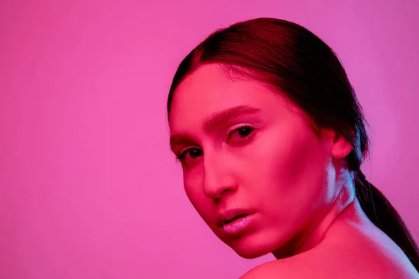 Schöne Ost-Frauenporträt isoliert auf rosa Studiohintergrund in Neonlicht, monochrom — Stockfoto