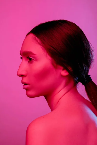 Linda mulher do leste retrato isolado no fundo do estúdio rosa em luz de néon, monocromático — Fotografia de Stock