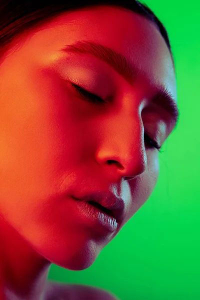 Gyönyörű keleti nő közelkép portré elszigetelt zöld háttér piros neon fény — Stock Fotó