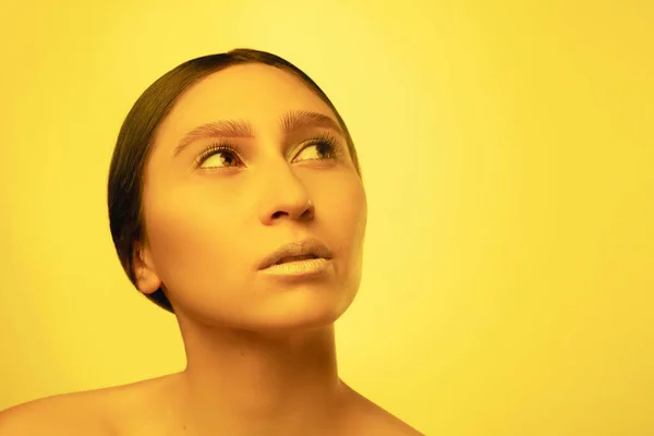 Gyönyörű keleti nő portré elszigetelt sárga stúdió háttér neon fény, monokróm — Stock Fotó