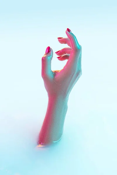 Закройте женскую руку жестом из молочной ванны с мягким светящимся неоновым светом — стоковое фото