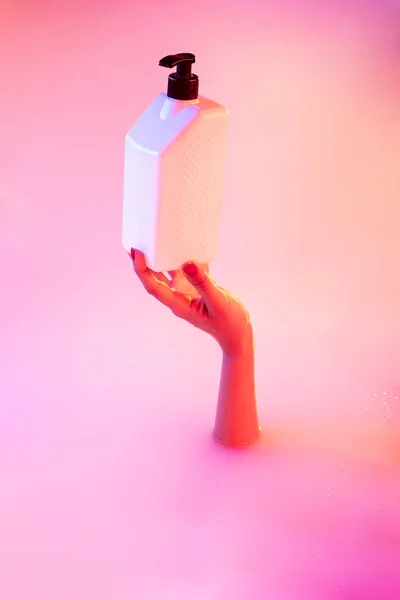 在霓虹灯下，用柔和的光芒将从奶浴中伸出手来的女性手紧紧地绑住 — 图库照片