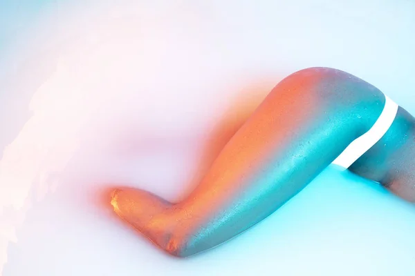 Закрыть женское тело в молочной ванне с мягким светящимся неоновым светом — стоковое фото