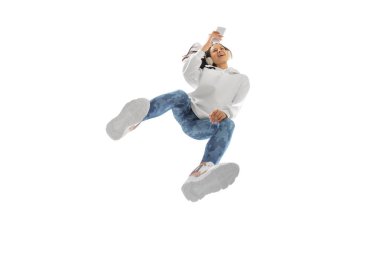 Modern sokak tarzı kıyafetli genç bir kadın beyaz arka planda izole edilmiş, alttan vurulmuş.