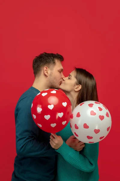 Hermosa pareja enamorada en el fondo rojo del estudio. Día de San Valentín, concepto de amor y emociones —  Fotos de Stock