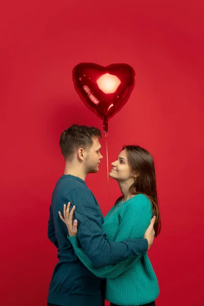 Belo casal apaixonado no fundo do estúdio vermelho. Dia dos Namorados, amor e emoções conceito — Fotografia de Stock