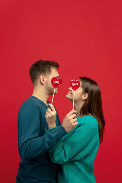 Hermosa pareja enamorada en el fondo rojo del estudio. Día de San Valentín, concepto de amor y emociones — Foto de Stock