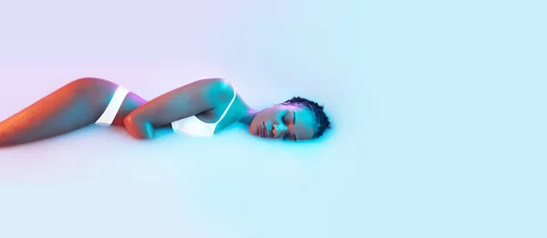Bellissimo corpo femminile nel bagno al latte con soffice incandescenza nella luce al neon blu-rosa — Foto Stock