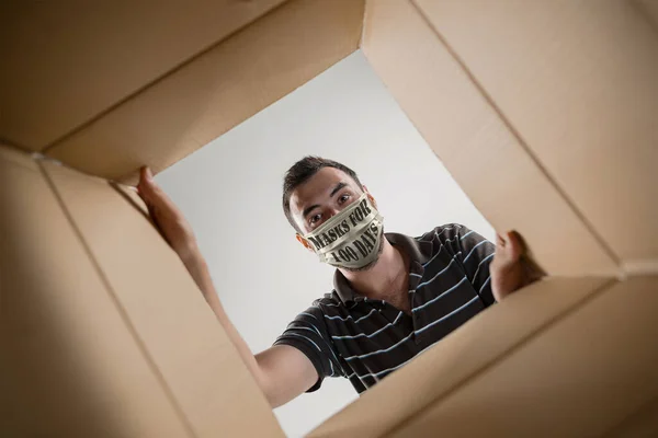 Hombre joven con máscara facial con máscaras de signos durante 100 días en EE.UU. abriendo el paquete postal más grande — Foto de Stock