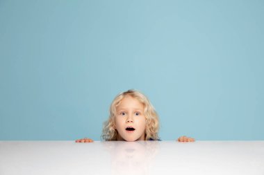 Mavi stüdyoda izole edilmiş mutlu kıvırcık çocuk. Mutlu, neşeli ve samimi görünüyor. Kopyalama. Çocukluk, eğitim, duygu kavramı