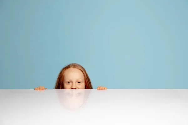 Menina ruiva feliz isolado no fundo do estúdio azul. Parece feliz, alegre, sincero. Espaço de cópia. Infância, educação, conceito de emoções — Fotografia de Stock