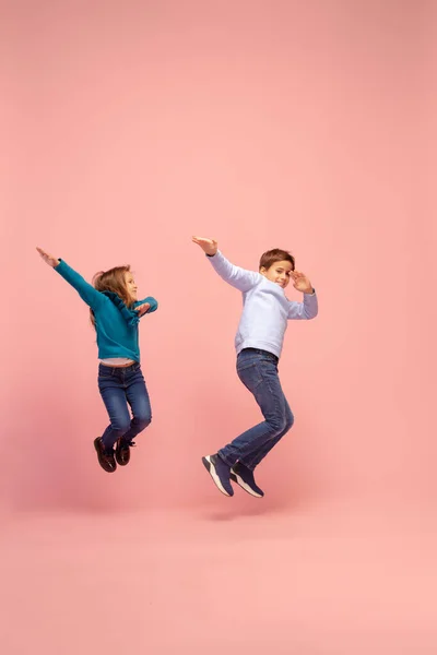 Crianças felizes isoladas no fundo do estúdio coral rosa. Pareces feliz, alegre, sincero. Espaço de cópia. Infância, educação, conceito de emoções — Fotografia de Stock