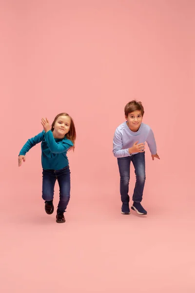 Crianças felizes isoladas no fundo do estúdio coral rosa. Pareces feliz, alegre, sincero. Espaço de cópia. Infância, educação, conceito de emoções — Fotografia de Stock
