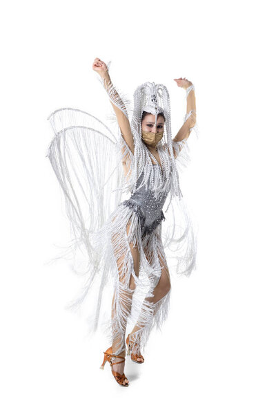 Beautiful young woman in carnival, stylish masquerade costume with feathers dancing on white studio background. Concept of holidays celebration, festive time, fashion