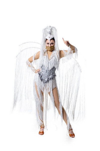 Beautiful young woman in carnival, stylish masquerade costume with feathers dancing on white studio background. Concept of holidays celebration, festive time, fashion