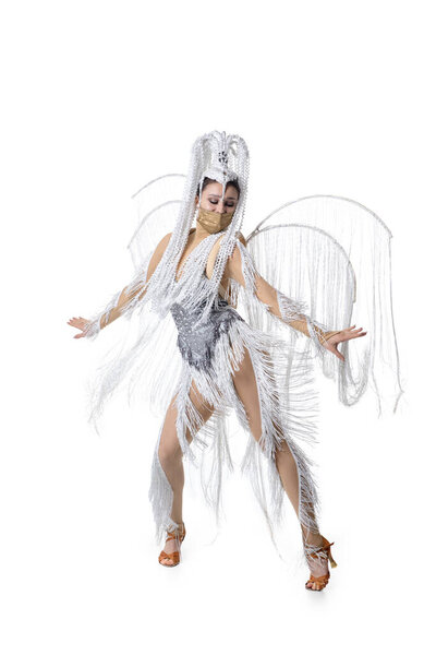 Beautiful young woman in carnival, stylish masquerade costume with feathers dancing on white studio background. Concept of holidays celebration, festive time, fashion