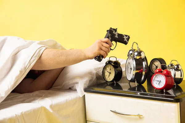 Man wakes up and hes mad at clock ringing, switches it off with the gun
