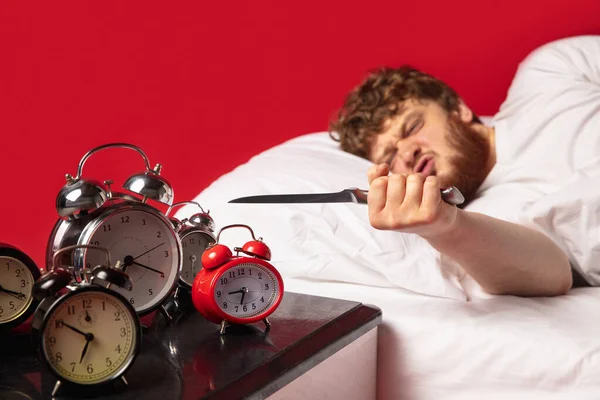 El hombre se despierta y se enoja con el timbre del reloj, lo apaga con un cuchillo de cocina — Foto de Stock