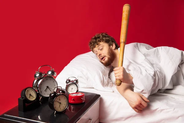 El hombre se despierta y se enoja con el timbre del reloj, lo apaga con el bate de béisbol — Foto de Stock