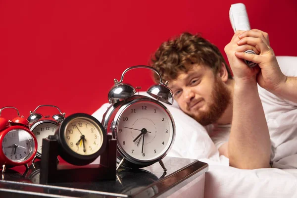 El hombre se despierta y se enoja con el timbre del reloj, lo apaga con documentos enrollados — Foto de Stock