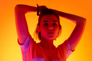 Kafkas kadın portresi turuncu stüdyo arka planında çok renkli neon ışıklarla izole edilmiş.