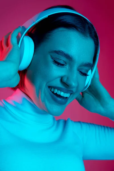 Blanke vrouwen portret geïsoleerd op roze studio achtergrond in veelkleurig neon licht — Stockfoto