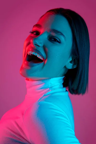 Blanke vrouwen portret geïsoleerd op roze studio achtergrond in veelkleurig neon licht — Stockfoto