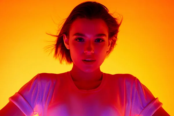Kaukasische Frauenporträt isoliert auf orangefarbenem Studiohintergrund in buntem Neonlicht — Stockfoto