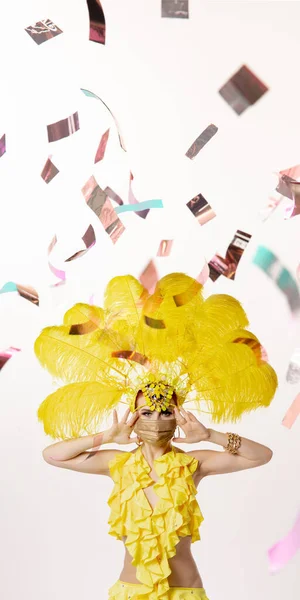 Mulher bonita no carnaval, traje de mascarada elegante com penas dançando no fundo do estúdio branco com confete brilhante — Fotografia de Stock