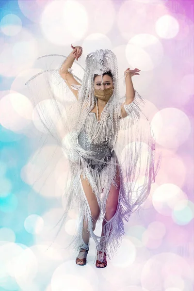 Mulher bonita no carnaval, traje de mascarada elegante com penas dançando no fundo do estúdio branco com bokeh brilhante — Fotografia de Stock