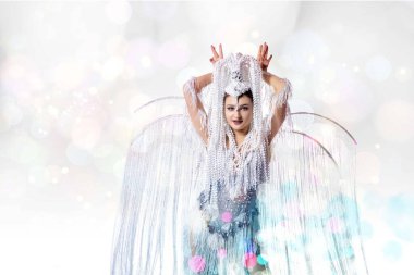 Karnaval içinde güzel bir genç kadın, şık bir maskeli balo kostümü beyaz stüdyo arka planında dans eden parlak konfetiyle
