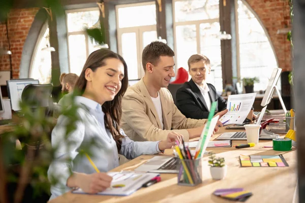 Jeunes collègues caucasiens travaillant ensemble dans un bureau en utilisant des appareils et des gadgets modernes — Photo