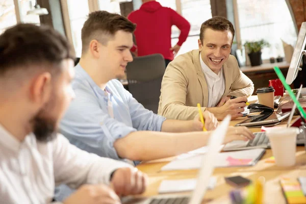 Jóvenes colegas caucásicos trabajando juntos en una oficina utilizando dispositivos y dispositivos modernos — Foto de Stock