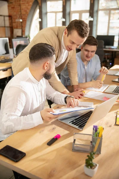 Jovens colegas caucasianos trabalhando juntos em um escritório usando dispositivos e gadgets modernos — Fotografia de Stock